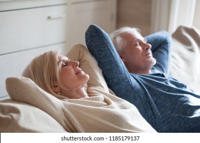 Calm senior mature couple relaxing on soft comfortable sofa having daytime nap together, carefree middle aged old family breathing fresh air enjoying no stress free peaceful weekend resting on couch