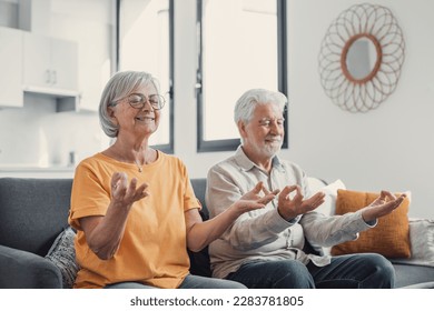 Calm senior middle aged couple practicing yoga together sitting in lotus pose on sofa, mindful peaceful mature man and woman meditating relaxing in living room at home, old people healthy lifestyle - Powered by Shutterstock