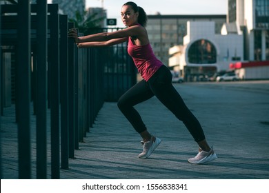 Calm Slim Sportswoman Putting Hands On The Banister And Using It In Her Training