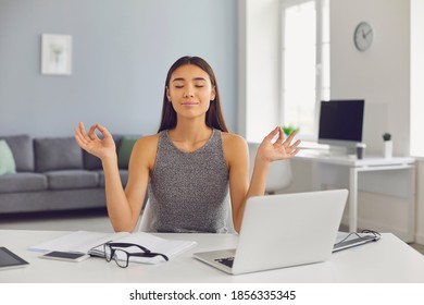 Calm smiling asian businesswoman relaxes and meditates with her eyes closed in her office during a break. Woman practices exercises to relieve stress. Office meditation concept. - Powered by Shutterstock