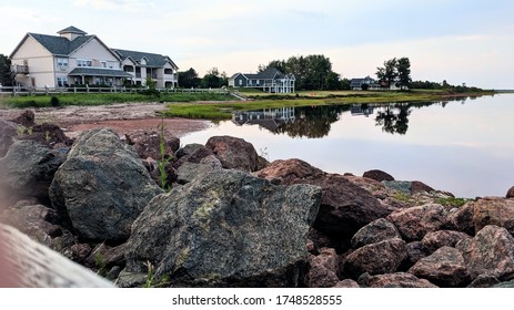 A calm summer evening in Northport pier, an area south of Alberton, PEI, creates still Atlantic Ocean waters that reflect a beautiful image of east coast waterfront cottages.