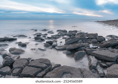 Calm Twilight on Rocky Shoreline With Gentle Waves Lapping Against Stones at Dusk - Powered by Shutterstock