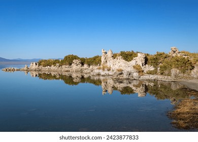 Calm water of Mono Lake Tufa State Natural Reserve California reflecting the mineral rock formations, clear blue sky and surrounding desert landscape environment, USA - Powered by Shutterstock