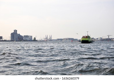 Calm water view with single ship and with industrial zone on the horizon, Amsterdam 