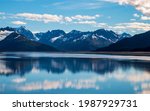 calm waters of Cook inlet near Anchorage, Alaska w snow capped mountains on the background.