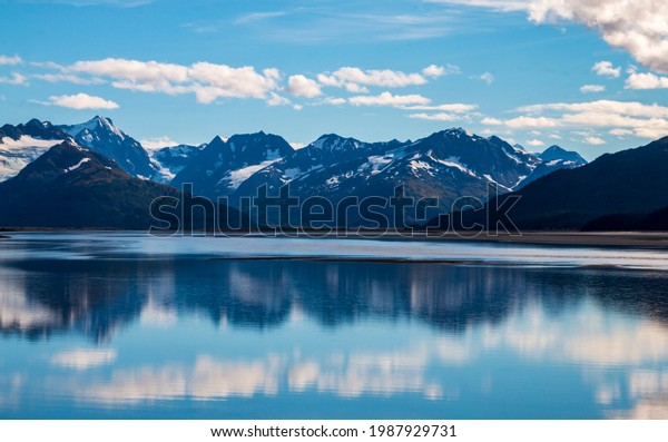calm waters of Cook inlet near\
Anchorage, Alaska w snow capped mountains on the\
background.