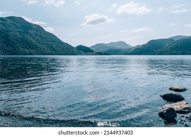 Calm Waters At Ullswater Lake With Mountains In The Distance In The Lake District National Park, Cumbria, UK During Summer.