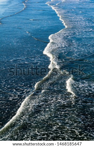 Similar – Ein Shortboard Sportler geht vom Strand auf das wellige Meer um zu Surfen. Blick von der Seite