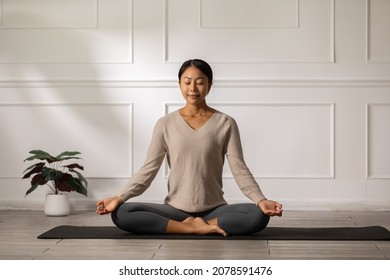 Calm of wellness Asian young woman sit on carpet breathing with yoga lotus pose,Yoga meditation of young healthy woman relax and comfortable at white cozy home,Yoga Exercise for Wellness Concept - Powered by Shutterstock