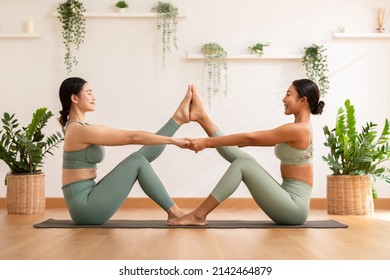 Calm of wellness Couple Asian young woman sit on yoga mat doing breathing exercise yoga boat pose or diamond shape together.Yoga meditation of two healthy female balancing body and relax at cozy home - Powered by Shutterstock