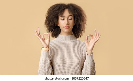 Calm woman relaxing, meditation, stress-free relief at work concept. Peaceful young african american lady, practicing yoga, breathing exercises with closed eyes, isolated on yellow background