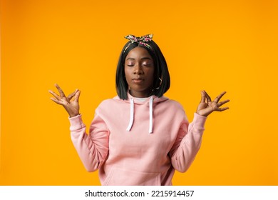 Calm Young African Woman Relaxing Meditating In Zen Pose Against Yellow Background