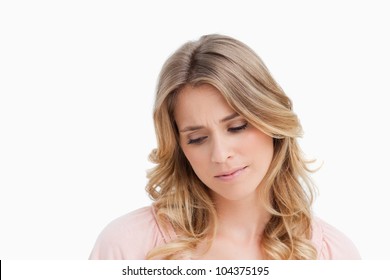 Calm young blonde woman looking down against a white background