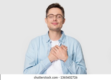 Calm young Caucasian male in glasses isolated on grey studio background hold hands on chest close to heart feel grateful, thankful European man in appreciation thanking fate. Gratitude concept - Powered by Shutterstock