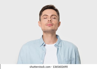 Calm young Caucasian male isolated on grey studio background enjoy pleasant smell or fragrance, relaxed European man in shirt breath deep, feel mindful inhaling fresh air. Stress free concept - Powered by Shutterstock