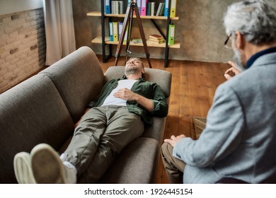 Calm young caucasian man lying on couch with closed eyes during psychotherapy session in office. Psychotherapy concept - Shutterstock ID 1926445154