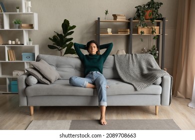 Calm Young Hispanic Woman Sit Relax On Couch In Living Room Take Nap Or Sleep At Home. Peaceful Latino Female Renter Rest On Sofa Breathe Fresh Ventilated Air Relieve Negative Emotions. Peace Concept.