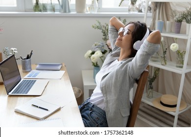 Calm Young Woman In Headphones Relax In Chair At Workplace Distracted From Computer Work Listen To Music, Happy Female In Headset Enjoy Good Quality Sound In Earphones, Rest At Workspace At Home