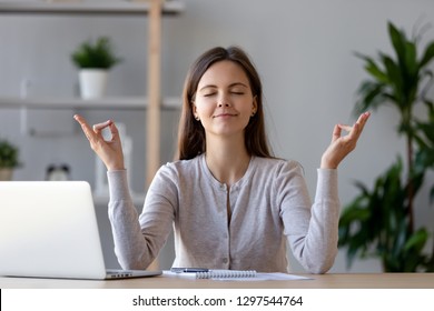 Calm Young Woman Worker Taking Break Doing Yoga Exercise At Workplace, Happy Mindful Female Student Meditating At Home Office Desk Feel Balance Harmony Relaxation, Stress Relief Zen At Work Concept