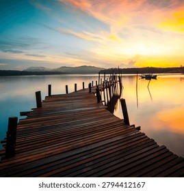 A calming sunset scene featuring a tranquil lake and a rustic wooden dock extending into the still water. Warm golden and orange hues reflect across the lake's surface, creating a serene atmosphere ideal for relaxation, meditation, travel, and nature appreciation. The peaceful setting captures the beauty of the outdoors at the end of a perfect day.