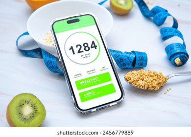 A calorie counting app displayed on a smartphone screen next to a tailor's measuring tape and a variety of healthy fruits and vegetables. Promoting mindful eating and nutrition tracking - Powered by Shutterstock