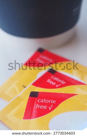 Calorie free sugar substitute packets sit next to a coffee cup