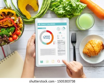 Calories counting , diet , food control and weight loss concept. woman using Calorie counter application on tablet at dining table with fresh vegetable salad - Shutterstock ID 1505303738
