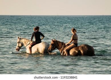 Calvi, Corsica, France - August 2018: People Ride Horses In The Sea At Sunset