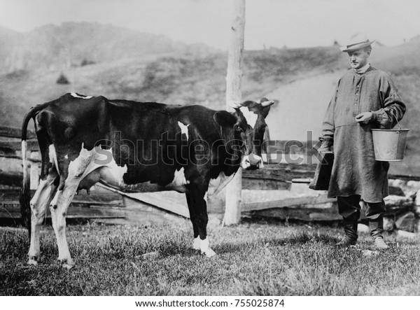 スモックと革のブーツを履いたカルビン クーリッジが乳牛に近づく 将来の大統領は バーモント州プリマスにある父親の農場にバケツと搾り台を運んだ 19年 23年 の写真素材 今すぐ編集