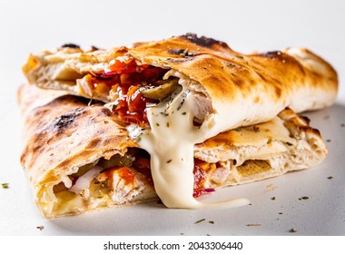 calzone pizza folded in half with meat, vegetables and cheese on a white background