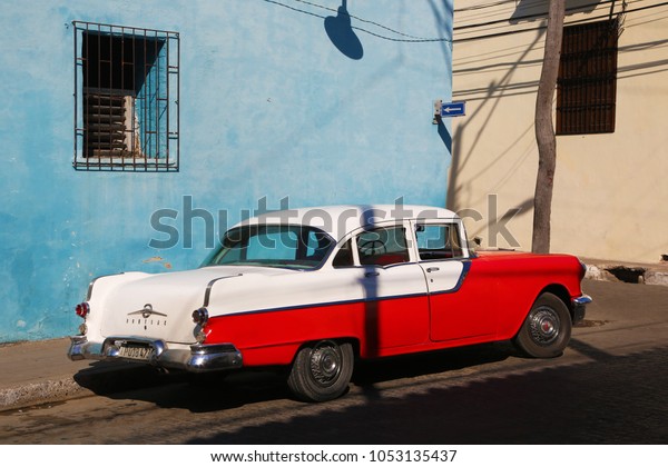 Camaguey, Cuba -\
March 7, 2018: Red and white classic car in front of blue building.\
The colors of cuban\
flag.