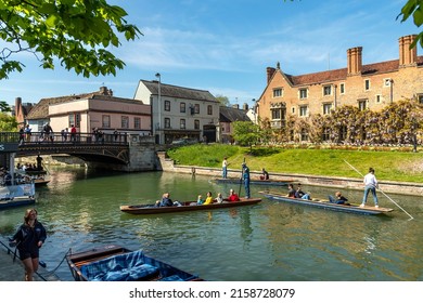 CAMBRIDGE, CAMBRIDGESHIRE, UK - APRIL 30, 2022: Tourists take to the the River Cam for a punt along the historic university city's waterway, getting a guided tour of its famous buildings and landmarks