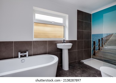 Cambridge, England - April 29 2019: Modern New Shower Room En Suite In White With Corner Walk In Cubicle, Bath Tub, Sink And Wall Mural