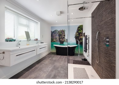 Cambridge, England - April 29 2019: Modern New Shower Room En Suite In White With Corner Walk In Cubicle, Bath Tub, Twin Sinks And Wall Mural