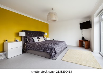 Cambridge, England - April 29 2019: Modern Furnished Bedroom With Bright Yellow Feature Wall In New Home