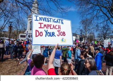 CAMBRIDGE, MA, USA - APRIL 15, 2017:  Protester at Tax Day March demanding that President Trump release his tax returns. Woman holding sign reading "Investigate. Impeach. Do Your Job."