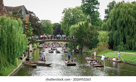Cambridge, UK - August 03, 2019:  Tourists were punting in the canal along the River Cam. Beautiful view of riversides for sightseeing with boats. Tourists watch punting trips from the old bridges.