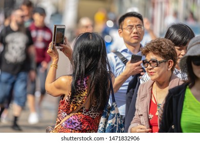 Cambridge, UK, August 1, 2019. Turists Walking Down And Taking Pictures At The Street Of Cambridge On A Busy Sunny Day In Front Of Kings College