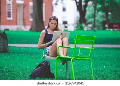 CAMBRIDGE, USA - JULY 14, 2019 : A students sit using laptop on chair at lawn in campus of the University in Cambridge, Massachusetts, USA .