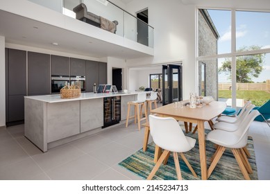 Cambridgeshire, England - May 1 2018: Modern Furnished Open Plan Luxury Kitchen Dining Room With Bifold Doors And Breakfast Bar.,