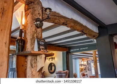 Cambridgeshire, UK - Circa July 2019: Detailed Interior Of An Old, Traditional English Pub And Restaurant Showing The Wooden Roof Beams. Patrons Can Be Seen In The Eating Area During A Busy Time.