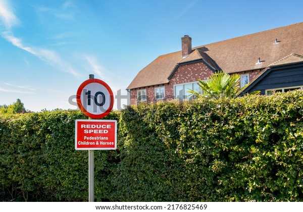 Cambridgeshire, UK - Circa July 2022: Isolated
view of a 10Mph road sign seen down a country lane, used by
pedestrians and horse riders. A large country house is seen over
the privet
hedge.