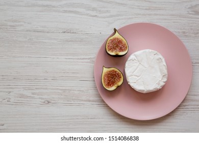 Camembert Or Brie With Figs On A Pink Plate On A White Wooden Surface, Top View. Flat Lay, Overhead, From Above. Space For Text.