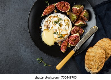 camembert cheese baked with  figs, nuts and honey, top view, black background
