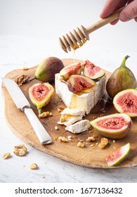 Camembert cheese with figs and nuts on wooden cutting board. Close up view. 