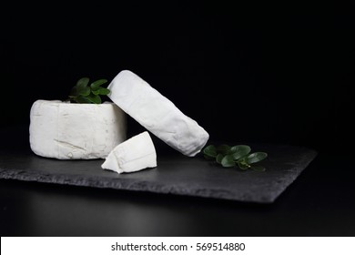 Camembert Cheese With Green Leaves On A Black Background