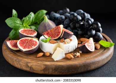 Camembert cheese platter with figs, grapes and nuts. Wooden cheese board - Powered by Shutterstock