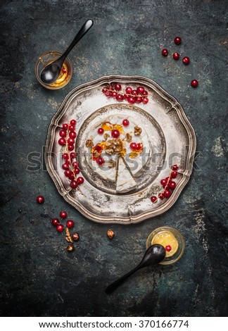 Camembert cheese served on a silver platter with berries and honey, top view