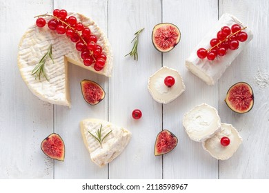 camembert and goat cheese decorated with slices of fig fruits, red currants and rosemary, on white wooden background, top view - Powered by Shutterstock