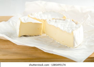 Camembert With Piece On White Wrapping Paper